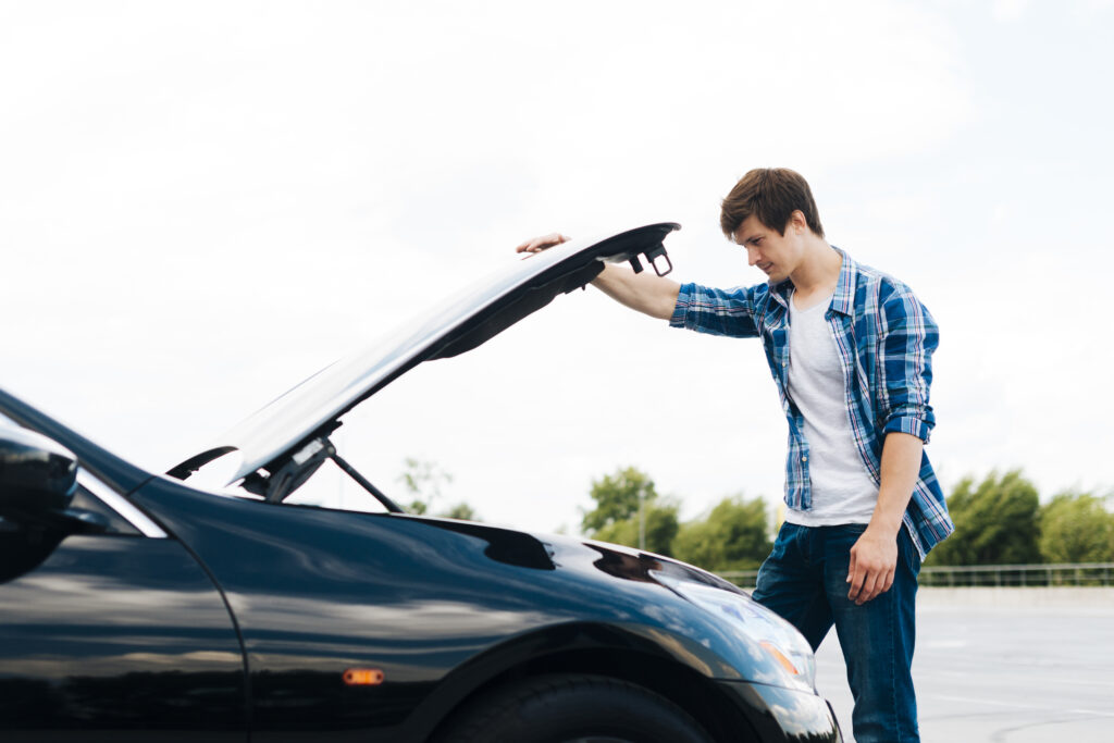 side view man opening car hood